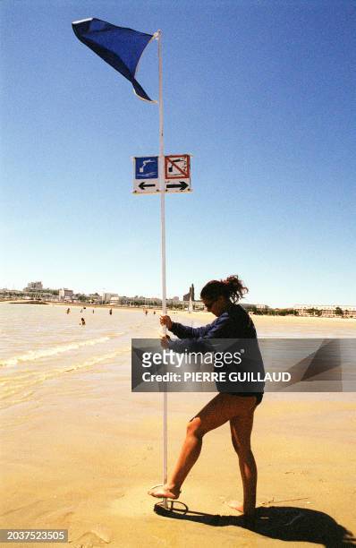 Un maître-nageur-sauveteur de la SNSM plante un pavillon bleu, le 29 juin 2001 sur une plage près de Royan, en Charente-Maritime. Le Pavillon bleu...