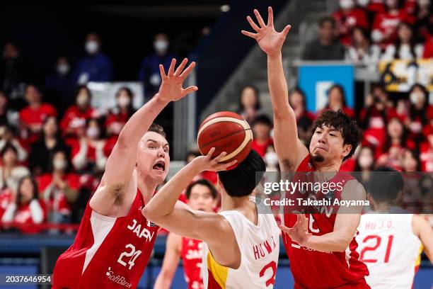 Mingxuan Hu of China drives to the basket against Makoto Hiejima and Joshua Hawkinson of Japan during the FIBA Basketball Asia Cup qualifier Group C...