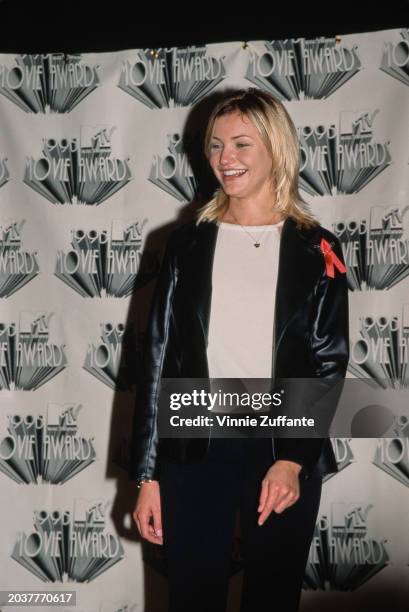 American actress Cameron Diaz, wearing a black leather jacket over a white sweater, with a heart-shaped pendant on a necklace, in the press room of...