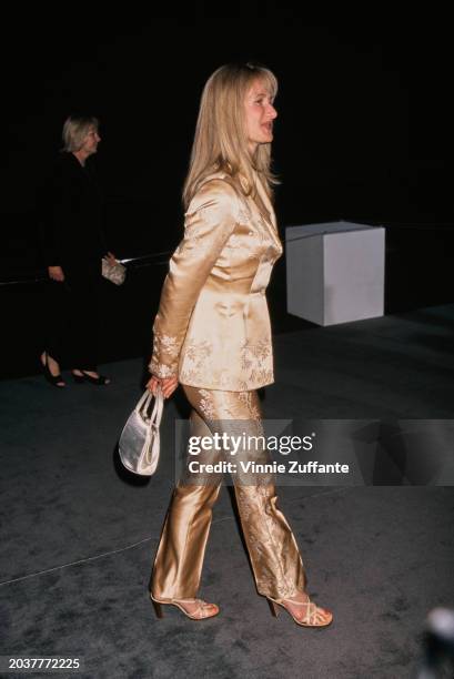 American actress Laura Dern, wearing a gold trouser suit, attends a fashion benefit for AIDS Project Los Angeles , held in the Barker Hangar at Santa...