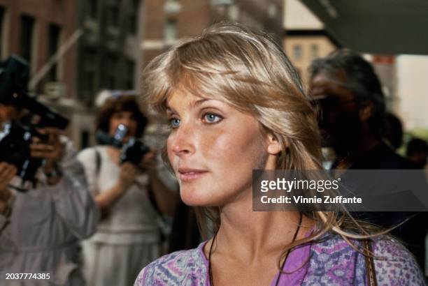 American actress Bo Derek, wearing a purple patterned outfit, with photographers in the background, United States, circa 1980.