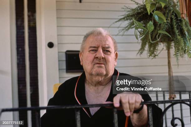 American comedian and actor Joe DeRita, wearing a black top with red and white trim, his left hand on a railing, United States, circa 1985. DeRita...
