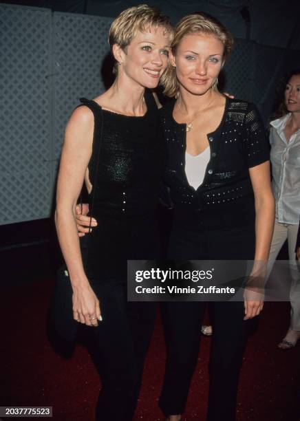 American–Canadian actress Lauren Holly, wearing a black sleeveless outfit, and American actress Cameron Diaz, who wears a black cardigan over a white...