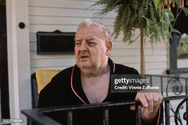 American comedian and actor Joe DeRita, wearing a black top with red and white trim, his left hand on a railing, United States, circa 1985. DeRita...