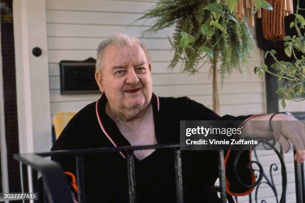 American comedian and actor Joe DeRita, wearing a black top with red and white trim, his left hand on a railing, United States, circa 1985. DeRita...