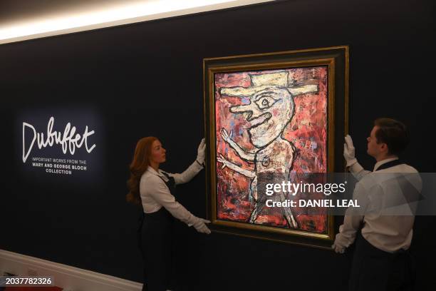 Staff members pose with an artwork entitled "Le Guilleret" by French artist Jean Dubuffet during a photocall ahead of the Modern & Contemporary art...