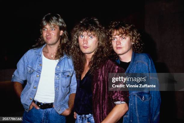 British singer, musician and songwriter Joe Elliott, wearing a denim jacket over a white t-shirt, British musician Rick Savage, who wears a purple...