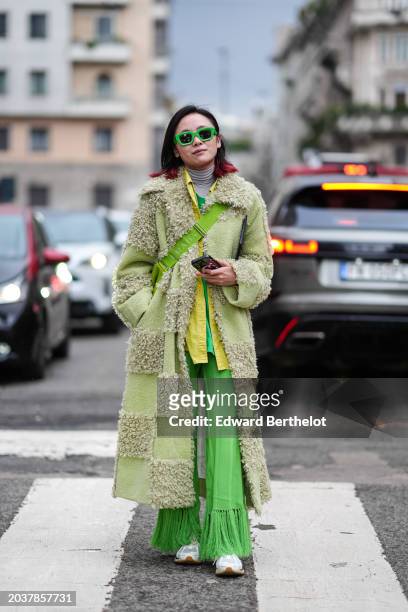 Guest wears green sunglasses, a gray turtleneck top, a green long fluffy with checkered / checked patterns, a yellow shirt, green fringed pants,...