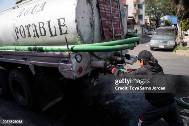 Worker connects a hose to a water truck outside an apartment complex in the Las Peñas neighborhood in Iztapalapa on February 27, 2024 in Mexico City,...