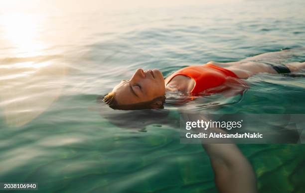 mid adult woman swimming in the calm sea water - woman underwater photos et images de collection