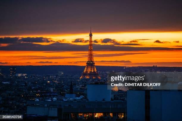 This photograph taken in Paris on February 27 shows the Eiffel Tower being illuminated at sunset.