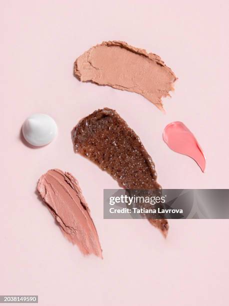 set of textured beauty products on pink background. brown body scrub, white face cream, lipstick swatches and pink gel moisturizer for healthy skin - pink lipstick smear stock pictures, royalty-free photos & images