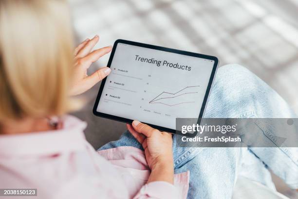 professional woman analyzing trending products graph on tablet - product test stockfoto's en -beelden