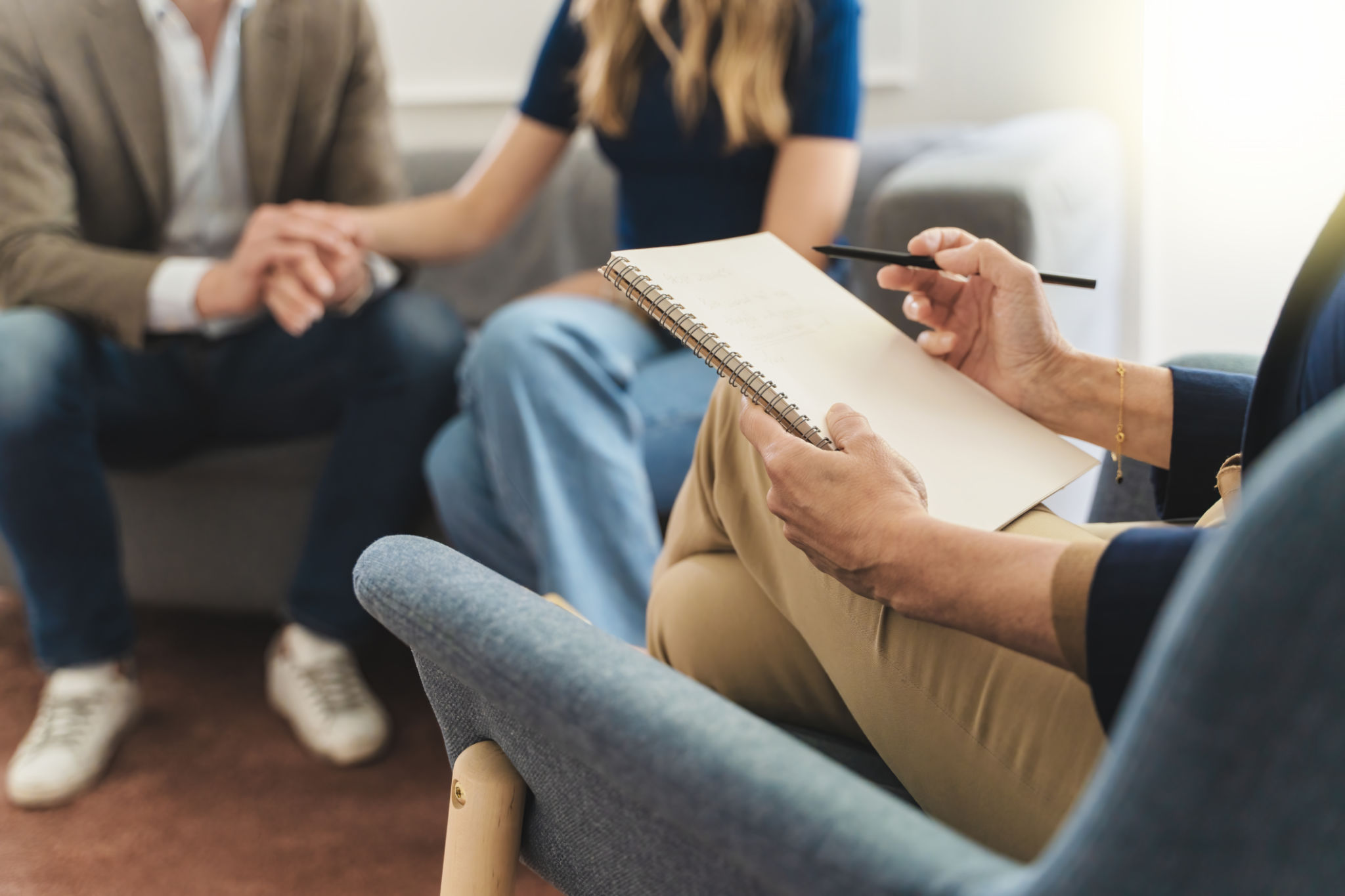 Couple Therapy Insight: Focus on Therapist's Notebook with Young Married Couple in Background Couple Therapy Insight: Focus on Therapist's Notebook with Young Married Couple in Background