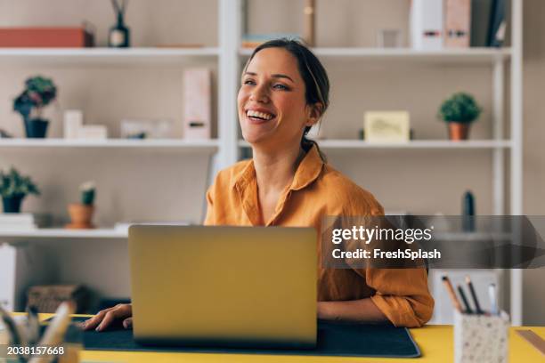 happy professional woman enjoying her workday at a sunny office desk - brightly lit office stock pictures, royalty-free photos & images