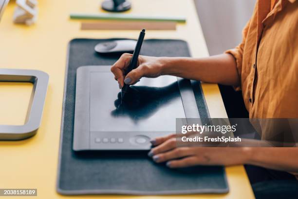 graphic designer working on a tablet at a creative modern desk - graphics tablet stock pictures, royalty-free photos & images