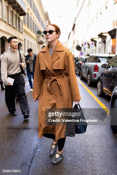 Guest is seen wearing black sunglasses, a beige trench, a grey t-shirt, gold necklaces, a black leather bag, black trousers and black studded leather...