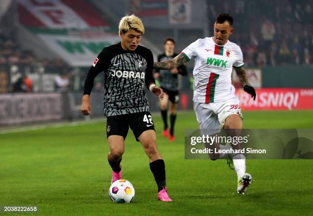 Ritsu Doan of SC Freiburg on the ball whilst under pressure from Iago of FC Augsburg during the Bundesliga match between FC Augsburg and Sport-Club...