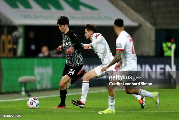 Merlin Roehl of SC Freiburg runs with the ball whilst under pressure from Elvis Rexhbecaj of FC Augsburg during the Bundesliga match between FC...