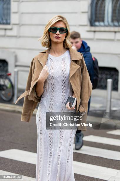 Guest wears brown wild leather jacket, white laced dress outside Luisa Spagnoli during the Milan Fashion Week - Womenswear Fall/Winter 2024-2025 on...
