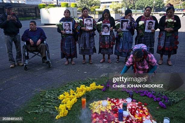 Relatives hold portraits of five victims of a highway eviction carried out by the military in 2012, during a Mayan ceremony outside the Palace of...