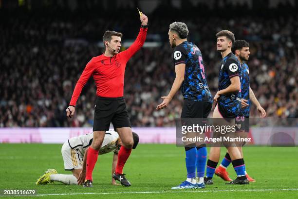 New Match Referee Carlos Fernandez Buergo shows a yellow card to Lucas Ocampos of Sevilla FC during the LaLiga EA Sports match between Real Madrid CF...