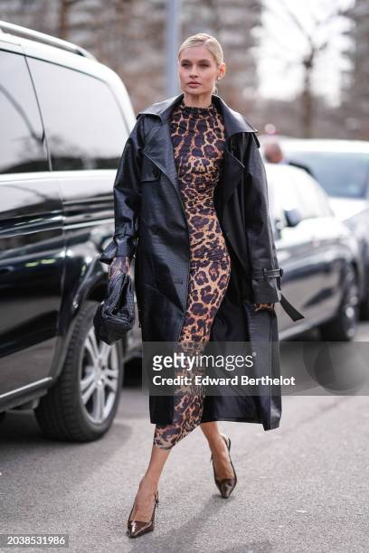 Guest wears a black leather coat, a brown and black leopard print pattern long dress , a black crocodile pattern leather bag, pointed shoes, outside...
