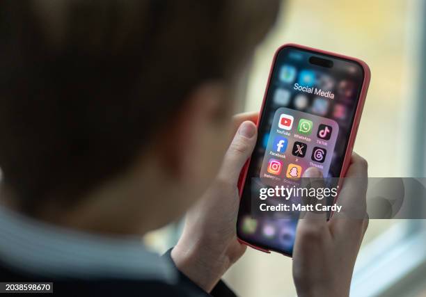 In this photo illustration a a 12-year-old school boy looks at a iPhone screen A 12-year-old boy looks at an iPhone screen showing various social...