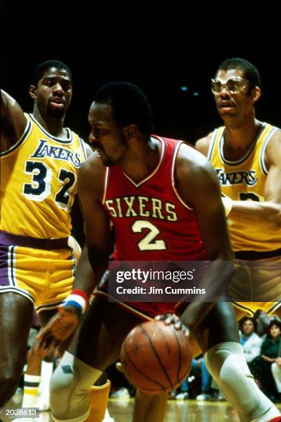 Moses Malone of the Philadelphia 76ers dribbles against Magic Johnson and Kareem Abdul-Jabbar of the Los Angeles Lakers during the 1983 NBA Finals at...