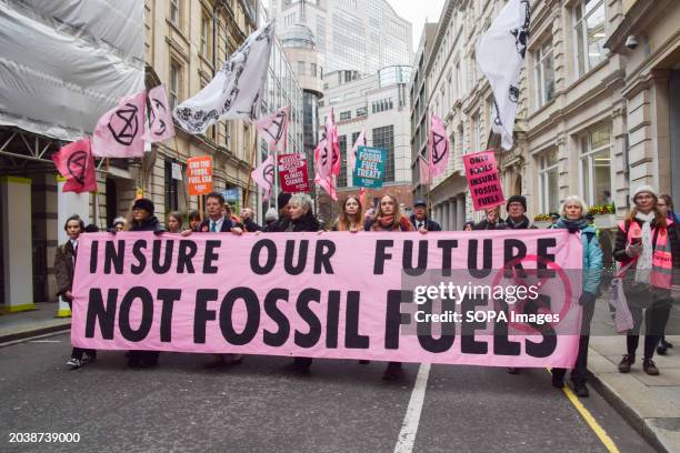 Protesters march with an anti-fossil fuel banner and placards during the demonstration. Extinction Rebellion activists marched in the City of London,...