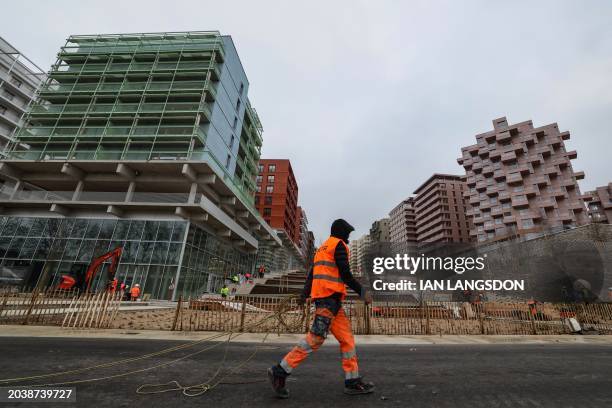 Worker walks past residential accommodation buildings at the construction site of the Olympic village where the athletes will be housed in...