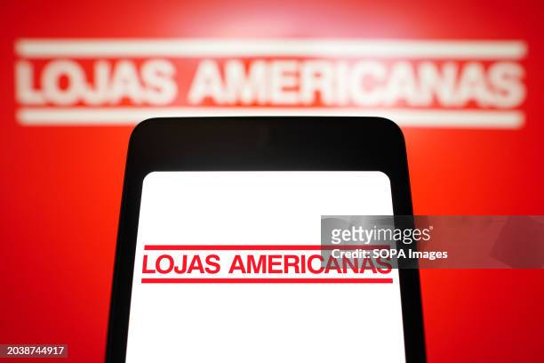 In this photo illustration, the Lojas Americanas logo is displayed on a smartphone screen and in the background.