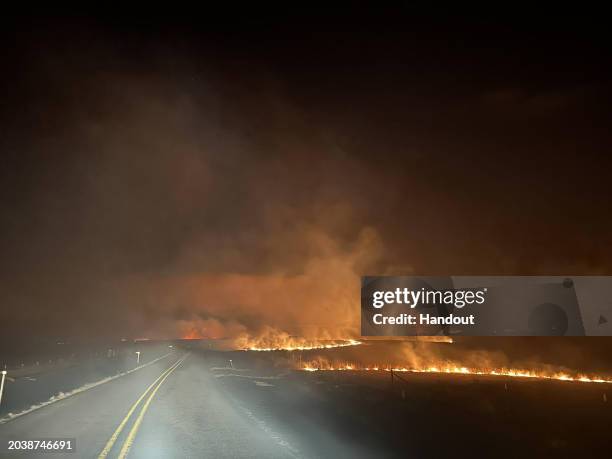 In this handout photo provided by the Texas A&M Forest Service, fire crosses a road in the Smokehouse Creek fire on the evening of February 27, 2024...