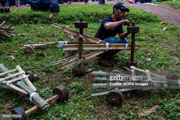Man is fixing bamboo karts in Pasir Angling Village. The Pasir Angling village community is reintroducing traditional bamboo and wood karts to...