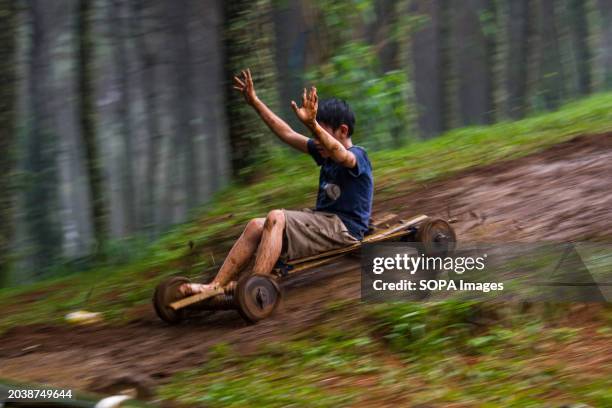 Kid is riding a bamboo kart down a hill in Pasir Angling Village. The Pasir Angling village community is reintroducing traditional bamboo and wood...