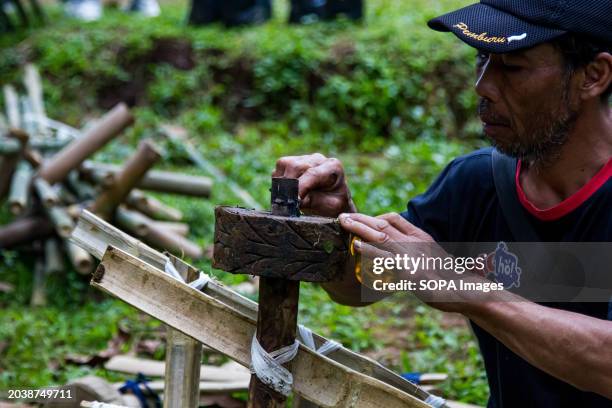 Man is fixing bamboo karts in Pasir Angling Village. The Pasir Angling village community is reintroducing traditional bamboo and wood karts to...