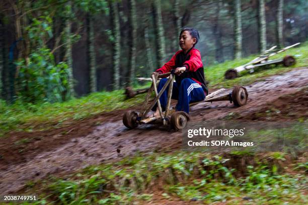 Kid is riding a bamboo kart down a hill in Pasir Angling Village. The Pasir Angling village community is reintroducing traditional bamboo and wood...