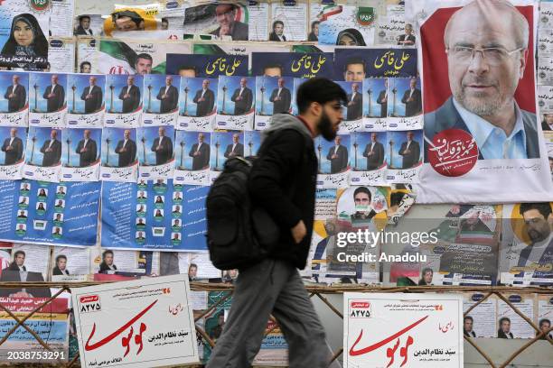 View of a billboard with candidate propaganda pictures, placards on it as a man walks past in a street of the Iranian capital Tehran on February 28,...