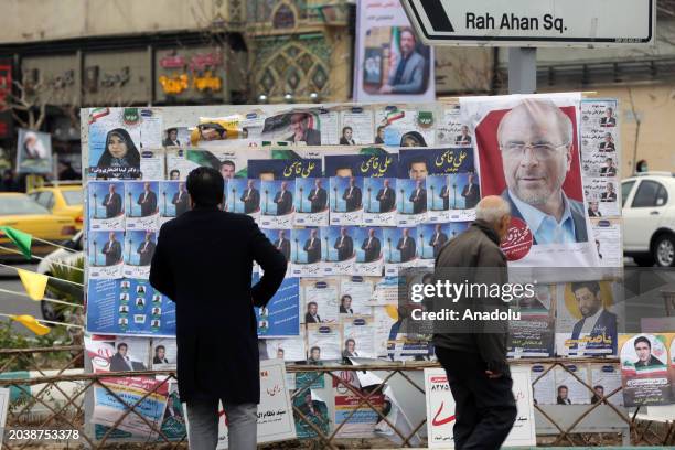 View of a billboard with candidate propaganda pictures, placards on it as a man walks past in a street of the Iranian capital Tehran on February 28,...