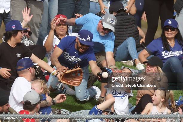 Fans reach for a home run ball by Jose Ramos of the Los Angeles Dodgers during a spring training exhibition against the Los Angeles Angels at the...