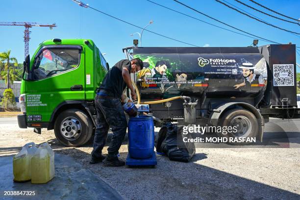Worker pours a container of used cooking oil to be recycled into biodiesel at a food shop on the Malaysian resort island of Langkawi on February 29,...