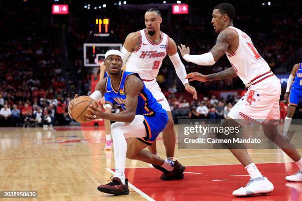 Shai Gilgeous-Alexander of the Oklahoma City Thunder is guarded by Jabari Smith Jr. #10 and Dillon Brooks of the Houston Rockets during the first...