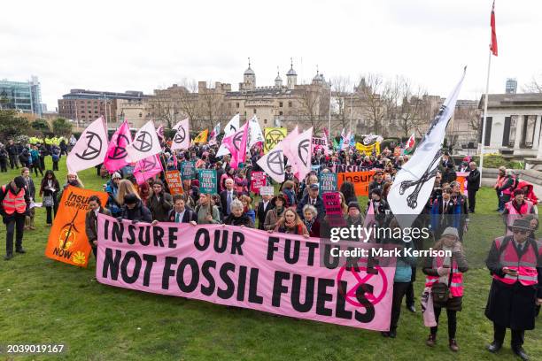 Climate activists from Extinction Rebellion assemble behind a banner in front of the Tower of London before a march to Lloyds of London in protest...