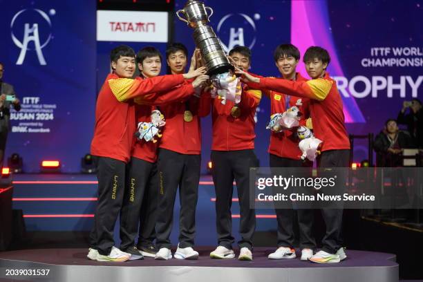 Liang Jingkun, Fan Zhendong, Ma Long, head coach Ma Lin, Wang Chuqin and Lin Gaoyuan pose with trophy and gold medals after winning the Final match...