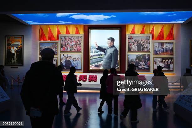 People look at a portrait of Chinese President Xi Jinping at the Museum of the Communist Party of China in Beijing on February 29 ahead of next...