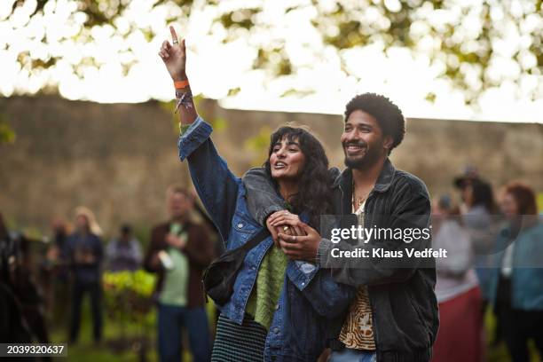 happy man with arm around girlfriend raising hand - festival goer stock pictures, royalty-free photos & images