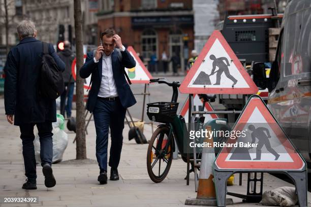 Man at work warning signs during street works by contractors in the City of London, the capital's financial district, on 28th February 2024, in...