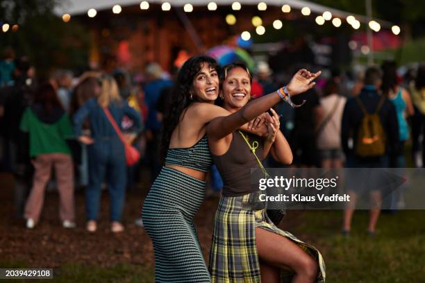 cheerful woman hugging female friend at concert - personas concierto fotografías e imágenes de stock