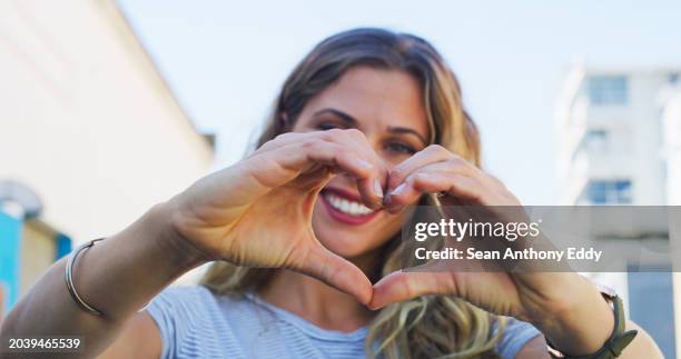 mani, cuore e sorriso di donna con segno di amore, cura ed empatia in ritratto in città, strada o città australia. compassione, emoji e volto del modello con felicità in vacanza con supporto o stile - donazione foto e immagini stock