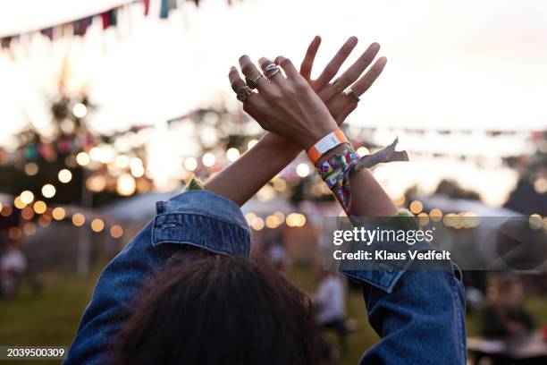 woman with hands raised dancing at music festival - festival stockfoto's en -beelden